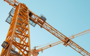 Upwards view of two large yellow cranes at work site